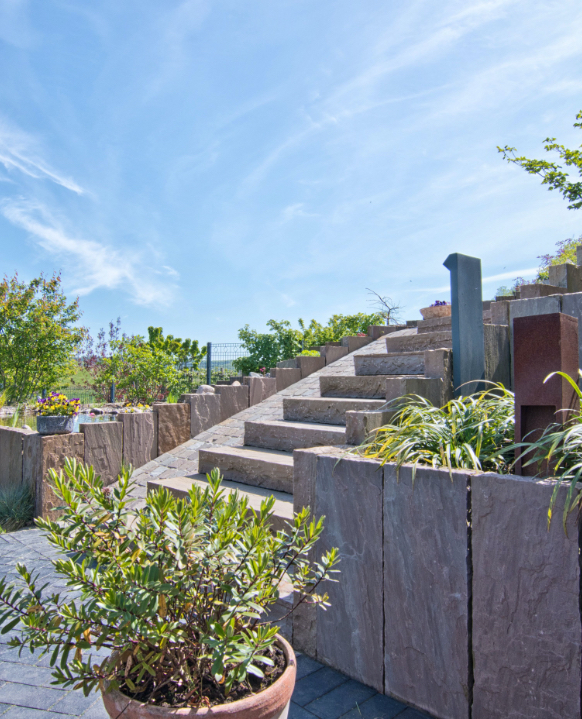 Ein Garten am Hang braucht Steintreppen und Steinwall.